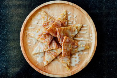 Yoğunlaştırılmış sütlü Roti, ahşap tabakta servis edilir..