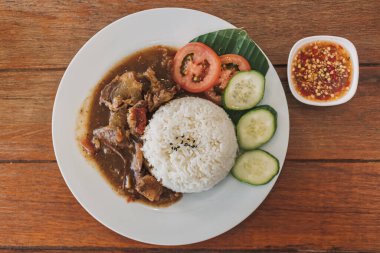 Beyaz tabakta servis edilen Tayland usulü biftek ve pilav..