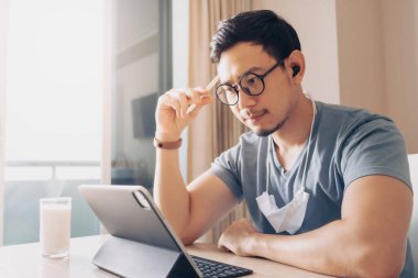 Mutlu adam tablet üzerinde çalışıyor. Evden çalışma kavramı üzerine..