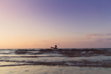 Renkli günbatımında küçük bir tekne denizde izole edilmiş. Yalnızlık kavramı.