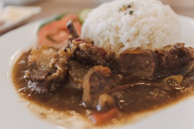 Beyaz tabakta servis edilen Tayland usulü biftek ve pilav..