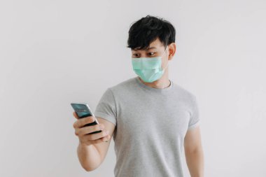 Adam maske takıyor ve beyaz arkaplanda izole edilmiş telefon uygulaması kullanıyor.