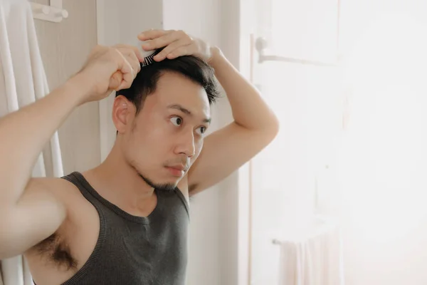 Homem está penteando o cabelo na casa de banho. — Fotografia de Stock