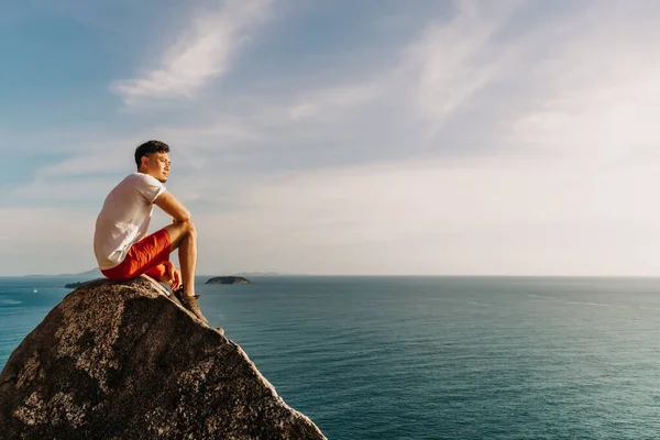Man rest on the sea cliff rock after finish his hike trail. — Stock Photo, Image