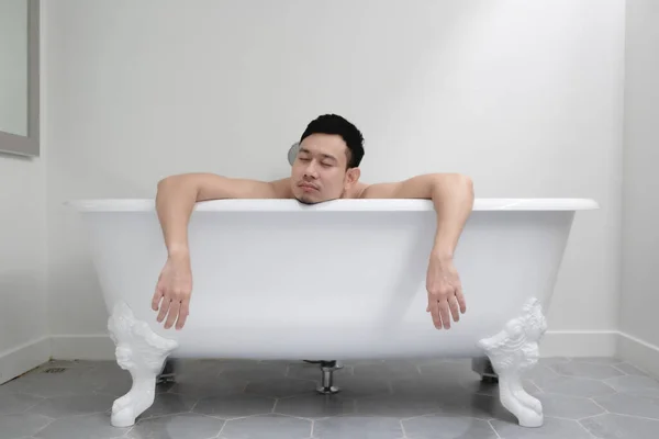 Sleepy man in white bathtub in concept of tired and relax. — Stock Photo, Image