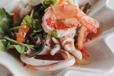 Süslü bir kasede servis edilen baharatlı Tayland deniz ürünleri salatası..