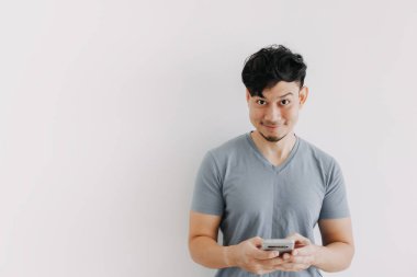 Gülümseyen adam beyaz duvardaki akıllı telefon uygulamasından memnun..