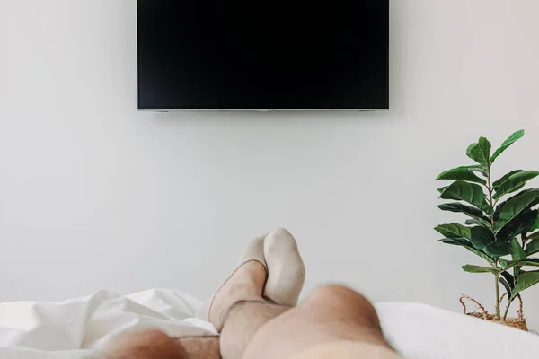 Людина спить на ліжку і дивиться телевізор. Концепція перебування вдома . — стокове фото