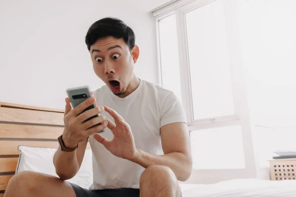 Cara de homem surpreendido enquanto olha para o smartphone em seu apartamento. — Fotografia de Stock