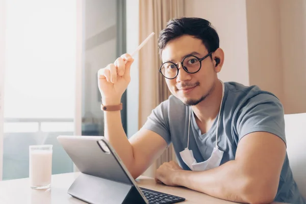 Feliz hombre está trabajando en su tableta en concepto de trabajo desde casa. —  Fotos de Stock