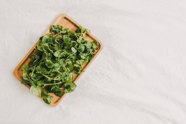 Tahta tabakta servis edilen yeşil ve taze Watercress yığını.