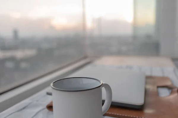 도시의 풍경을 담은 랩탑 과 화이트 커피 컵 이 있습니다. 직장에 대한 개념. — 스톡 사진