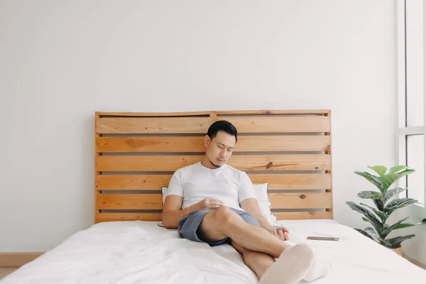 Asiático homem adormece na cama com o telefone em sua mão. — Fotografia de Stock