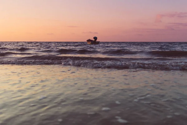 Petit bateau isolé sur la mer au coucher du soleil coloré. Concept de solitude. — Photo