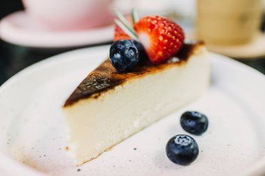 Beyaz tabakta servis edilen yanmış çilekli kek..