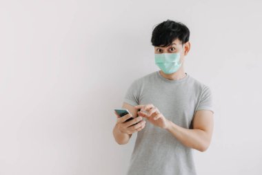 Adam maske takıyor ve beyaz arkaplanda izole edilmiş telefon uygulaması kullanıyor.