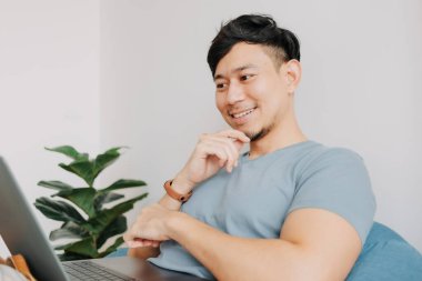 Mutlu adam evde kalırken bilgisayarla çalışıyor. Evde çalış..