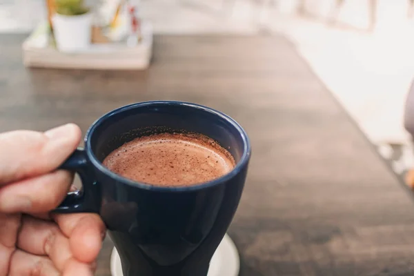 Tangan memegang secangkir cokelat panas di kafe. — Stok Foto