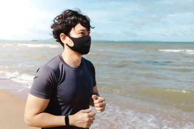 Adam yaz sabahı plajda maskeyle koşuyor..