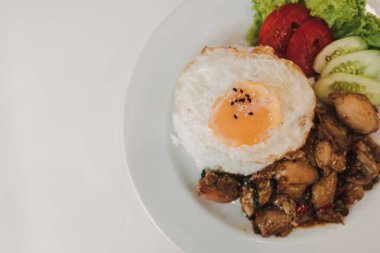 Fesleğenli pilav kızarmış tavuk ve kızarmış yumurta beyaz tabakta servis edilir..