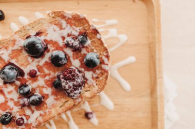 Böğürtlenli tost ekmeği ve ahşap tabakta konsantre süt..