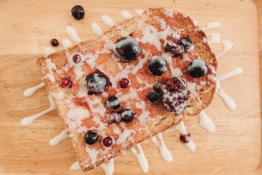 Böğürtlenli tost ekmeği ve ahşap tabakta konsantre süt..