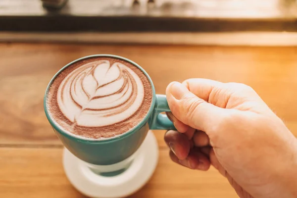 Cangkir kopi biru dengan seni latte penuh di atas meja kayu. — Stok Foto