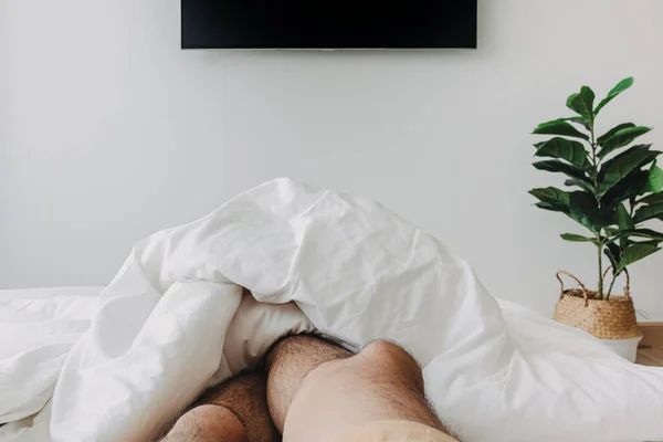 Persoon die op het bed slaapt en televisie kijkt. Begrip "thuis blijven". — Stockfoto