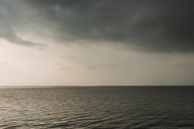 Gökyüzünde fırtınalı bulutlarla gün batımı okyanusu.