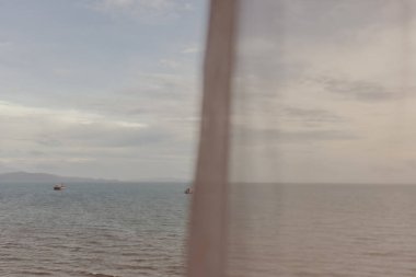 Yazın ince beyaz perdenin arasından okyanus manzarası.