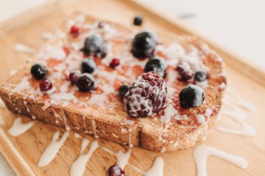 Böğürtlenli tost ekmeği ve ahşap tabakta konsantre süt..
