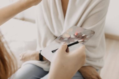 Makyaj sanatçısı müşteriye makyaj araçları kullanıyor.