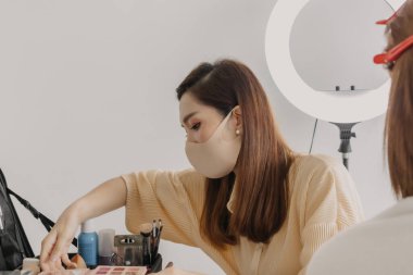 Makyajcı kadın işte ve modeline makyaj yapıyor..