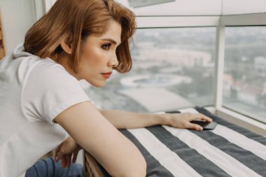 Kadın dinleniyor ve elinde akıllı telefonuyla odada dinleniyor..