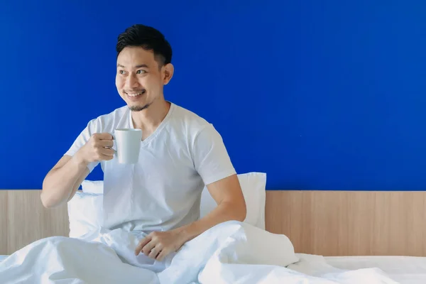 Feliz hombre despierta en su cama en el fondo del espacio de copia azul. — Foto de Stock