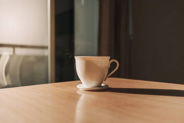 Горячая чашка напитка на столе в солнечном свете спокойного утра. — стоковое фото
