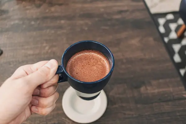 Ręczne trzymanie filiżanki gorącego kakao w kawiarni. — Zdjęcie stockowe
