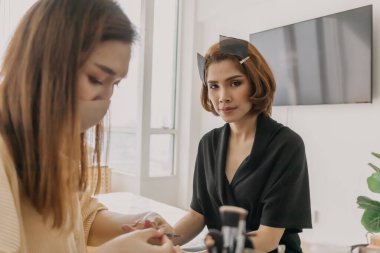 Makyajcı kadın işte ve modeline makyaj yapıyor..