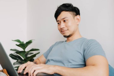 Mutlu adam evde kalırken bilgisayarla çalışıyor. Evde çalış..