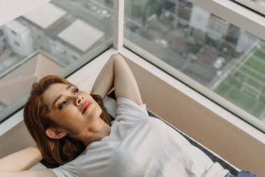 Kotlu ve beyaz tişörtlü güzel bir kadın dairesinde rahatlıyor..