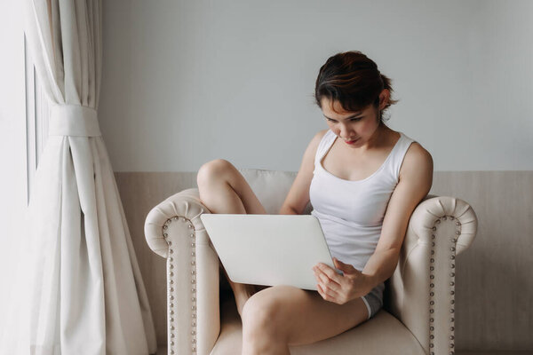 Woman works and relax with laptop on the sofa. Concept of work from hotel.