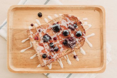 Böğürtlenli tost ekmeği ve ahşap tabakta konsantre süt..