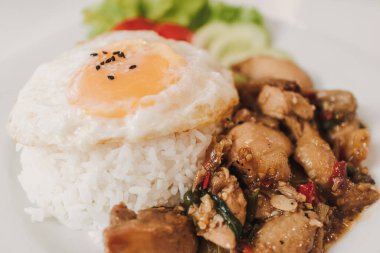 Fesleğenli pilav kızarmış tavuk ve kızarmış yumurta beyaz tabakta servis edilir..