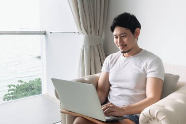 Otelde deniz manzaralı mutlu bir adam çalışıyor. Kalıcılık kavramı.