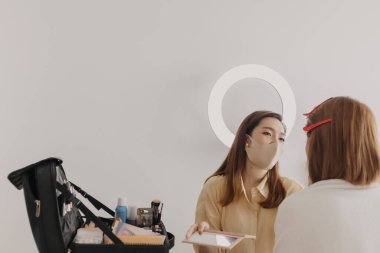 Makyajcı kadın işte ve modeline makyaj yapıyor..