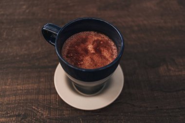 Sıcak kakao içeceği, ahşap masada mavi bardakta..