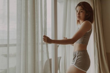 Çekici kadın otelin perdesinin arkasındaki manzaraya bak..