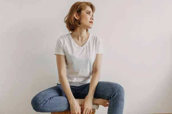 멋있어 보이는 하얀 티셔츠를 입은 여자 가 아파트 방에서 긴장을 푸는 모습. — 스톡 사진