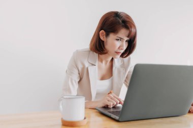 Çalışan kadın ofis masasında beyaz arka planda dizüstü bilgisayar kullanıyor..