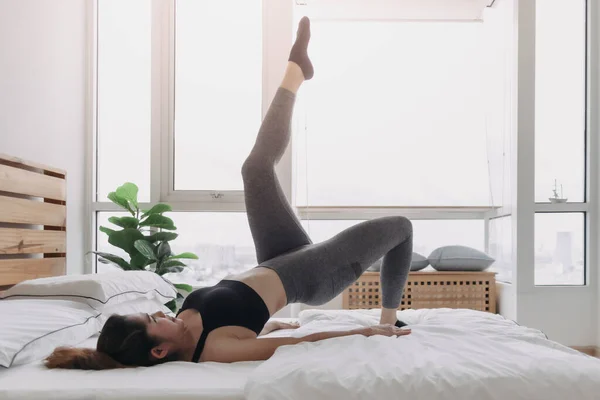 Woman does Alternate Leg Raise workout in her bedroom apartment. — Stock Photo, Image